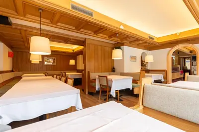 a dining room with white tables and chairs at Hotel Oswald in Canazei