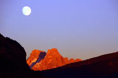 a moon rising over the mountains at sunset at Apartments Trettel in Tesero