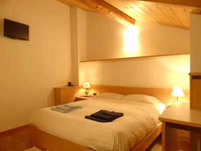 a bedroom with a large white bed and two lamps at Apartments Trettel in Tesero