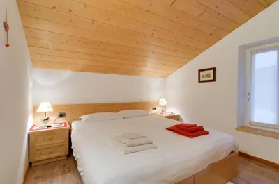 a bedroom with a white bed with wooden ceilings at Apartments Trettel in Tesero