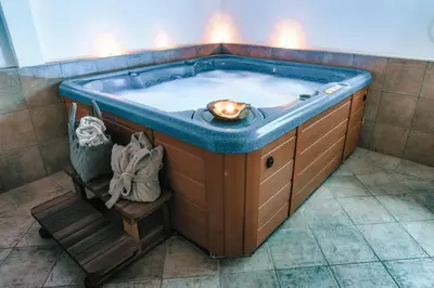 a hot tub with a bluevisor in a bathroom at Strahlerhof in Appiano sulla Strada del Vino