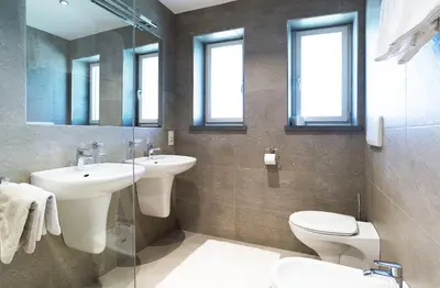a bathroom with two sinks and a toilet and mirrors at Strahlerhof in Appiano sulla Strada del Vino