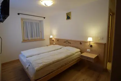 a small bedroom with a bed and a table at Vajolet in Campitello di Fassa