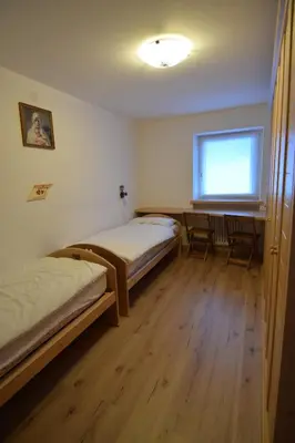 a room with two beds and a table and a window at Vajolet in Campitello di Fassa