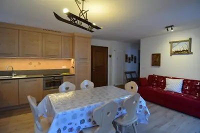 a kitchen and a living room with a table and a couch at Vajolet in Campitello di Fassa