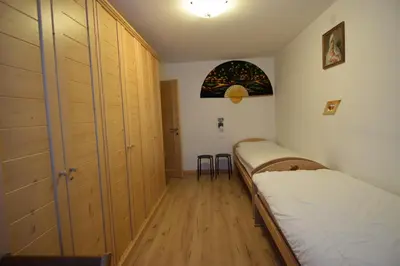 a bedroom with two beds and wooden cabinets at Vajolet in Campitello di Fassa