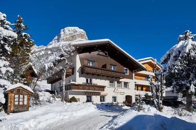 a building in the snow with a mountain at Alpin Relais B&B Villa Melisse in Colfosco