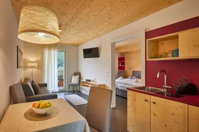 a kitchen and living room with a table with a bowl of fruit at Alpin Relais B&B Villa Melisse in Colfosco