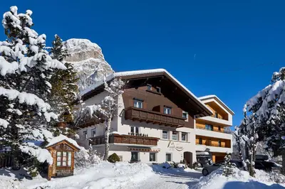 a building in the snow with snow covered trees at Alpin Relais B&B Villa Melisse in Colfosco