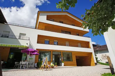 a building with a purple umbrella in front of it at Alpin Relais B&B Villa Melisse in Colfosco
