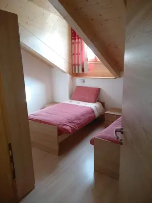 a small bedroom with two beds in a attic at Ciasa Savoy in Vigo di Fassa