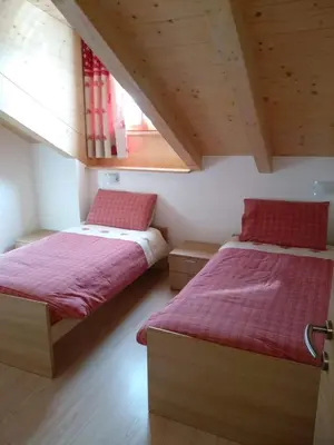 a bedroom with two beds with red sheets at Ciasa Savoy in Vigo di Fassa