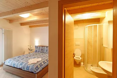 a bedroom with a bed and a bathroom with a sink at Ciasa Savoy in Vigo di Fassa