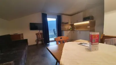 a living room with a kitchen and a table with a box at Haus Sonnegg in Marlengo