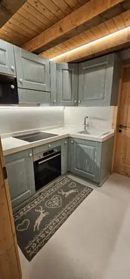a kitchen with blue cabinets and a sink and a rug at Appartamento Le Pale in Alleghe