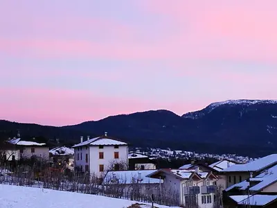 a town in the snow with mountains in the background at Dolomiti Di Brenta in Ronzone