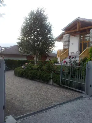 a fence in front of a house with a tree at Dolomiti Di Brenta in Ronzone