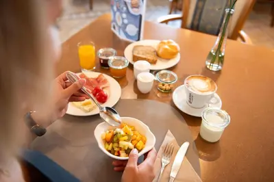 a woman eating a bowl of food on a table at Cristallo B&B in Castelrotto