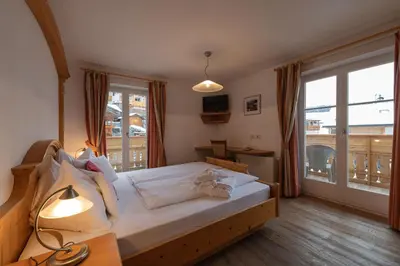a bedroom with a large bed and a large window at Cristallo B&B in Castelrotto