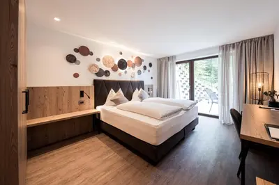 a bedroom with a large bed and a desk at Hotel Berghang in Collepietra