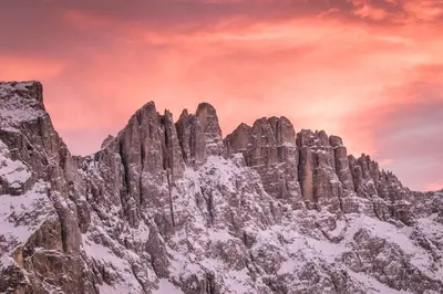 a mountain covered in snow and a cloudy sky at Hotel Berghang in Collepietra