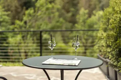 two wine glasses sitting on a table on a balcony at Hotel Berghang in Collepietra
