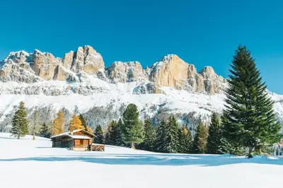 a cabin in the snow in front of a mountain at Hotel Berghang in Collepietra