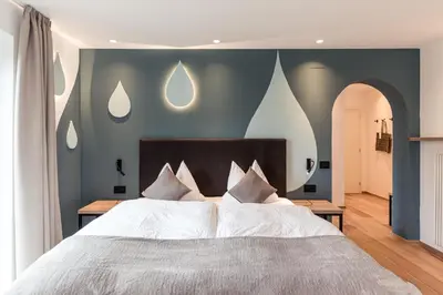a bedroom with a large bed with blue walls at Hotel Berghang in Collepietra