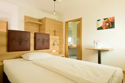 a bedroom with a white bed in a room at Gasthof Hotel Terzer in Cortaccia