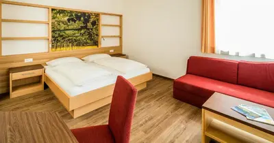 a small room with a bed and a red chair at Gasthof Hotel Terzer in Cortaccia