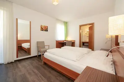 a bedroom with a large white bed and a mirror at Gasthof Hotel Terzer in Cortaccia
