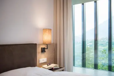 a bedroom with a bed and a lamp and a window at Art & Nature Chalet Anna in Schenna