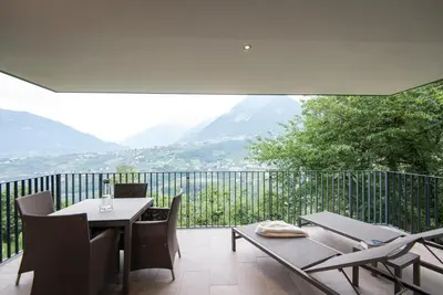 a balcony with a table and chairs and mountains at Art & Nature Chalet Anna in Schenna