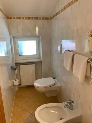 a white bathroom with a toilet and a window at B&B MARINA contacless check in in Santa Cristina in Val Gardena