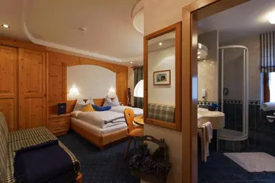 a hotel room with a bed and a bathroom at Garni Raetia in Corvara in Badia