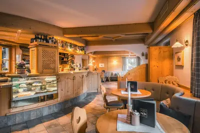 a restaurant with tables and chairs and a counter at Garni Raetia in Corvara in Badia