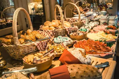 a table filled with baskets of bread and other food at Garni Raetia in Corvara in Badia