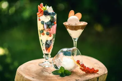 two glasses of desserts sitting on a wooden table at Garni Raetia in Corvara in Badia