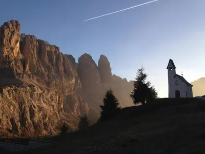 a church on top of a hill with a mountain at Garni Raetia in Corvara in Badia