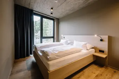 a bedroom with a bed with white sheets and a window at Panoramic Suites Winzerhöhe in Schenna