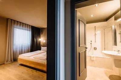 a bathroom with a bedroom with a bed and a sink at Panoramic Suites Winzerhöhe in Schenna