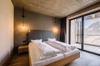 a bedroom with a bed and a large window at Panoramic Suites Winzerhöhe in Schenna