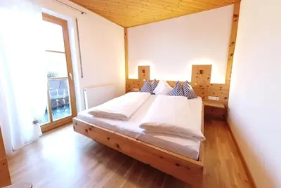 a large bed in a room with a large window at Grumserhof in Merano