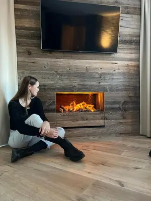 a woman sitting on the floor in front of a fireplace at B&B Boutique Apartment Oberwiesen in Brunico