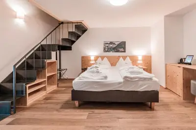 a bedroom with a bed and a staircase at B&B Boutique Apartment Oberwiesen in Brunico