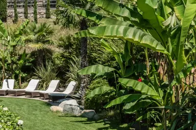 a garden with white lounge chairs and plants at Residence Fischerhof in Tirolo
