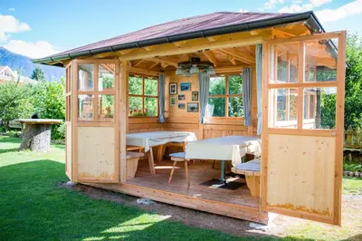 a wooden gazebo with tables and chairs in the grass at Pension Haus am See in Naz-Sciaves
