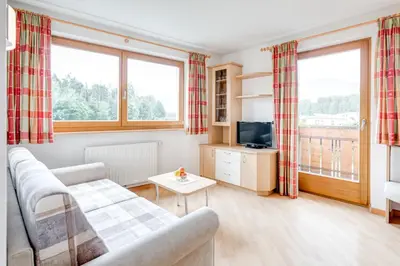 a living room with a couch and a tv at Pension Haus am See in Naz-Sciaves