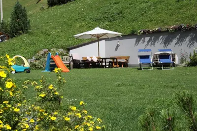 a backyard with a table and chairs and an umbrella at Garnì La Grambla in Selva di Val Gardena