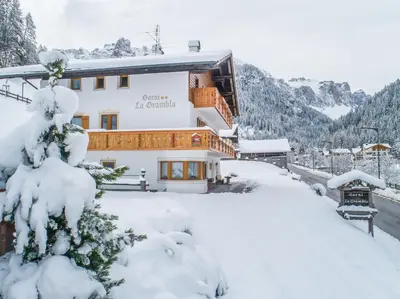 a building covered in snow with snow covered trees at Garnì La Grambla in Selva di Val Gardena